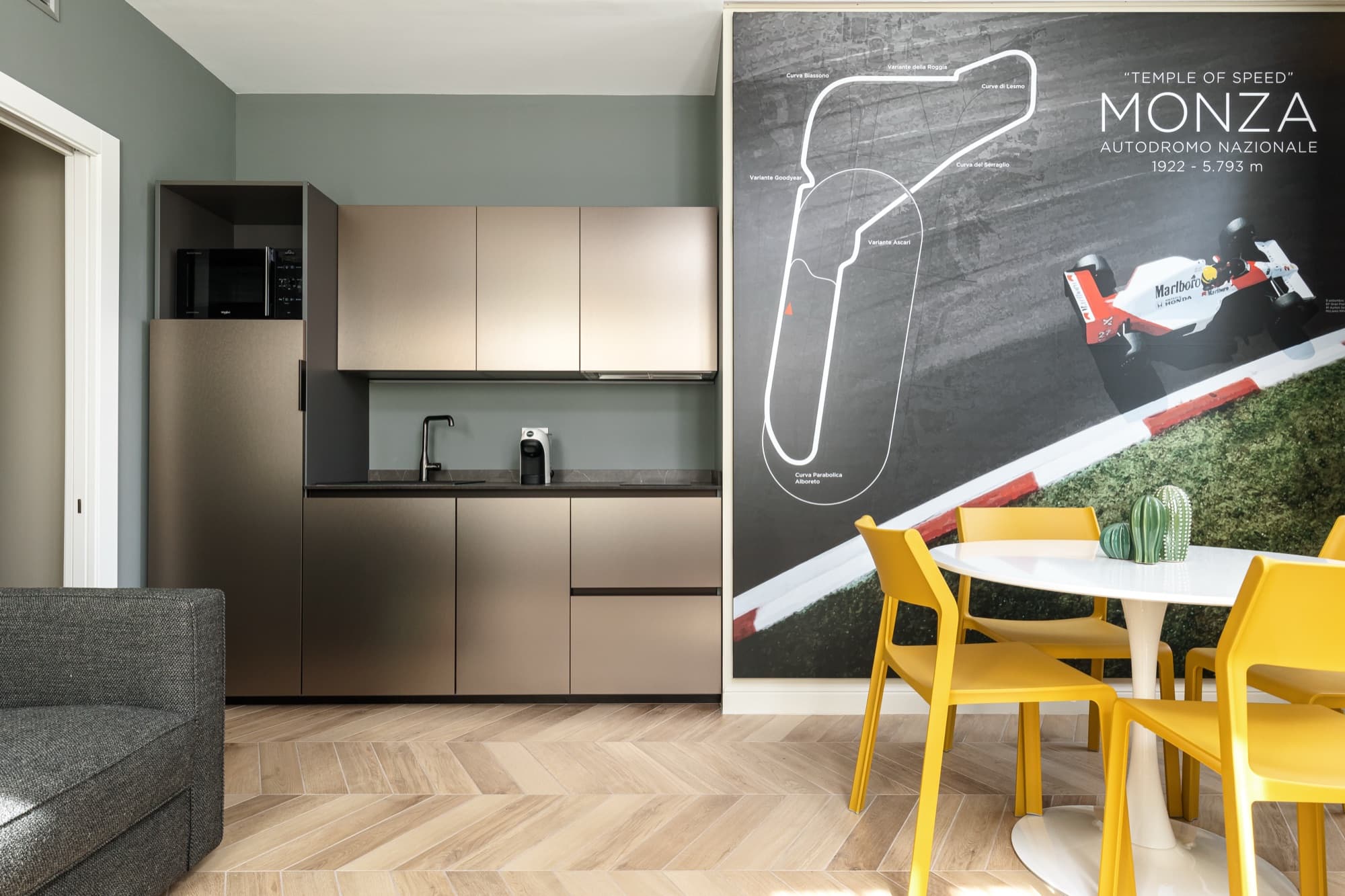Suite di Casa Duomo Monza con angolo cucina, sedie gialle e parete dedicata all'Autodromo