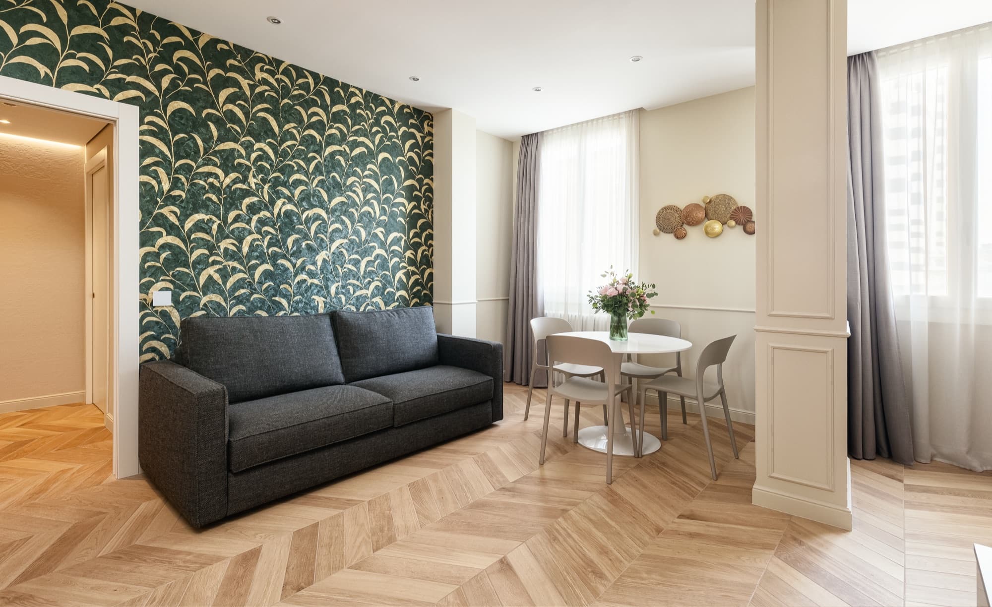 Suite di Casa Duomo Monza con carta da parati botanica verde, divano e zona pranzo