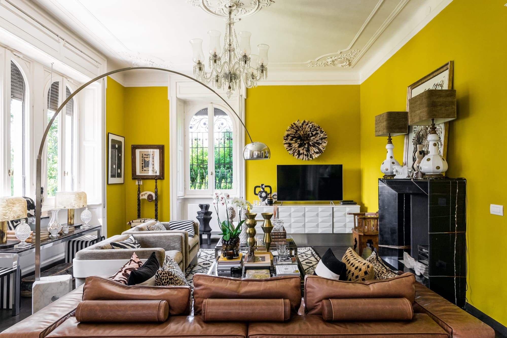 Soggiorno con pareti gialle, lampadario e camino nella Malene Birger Residence